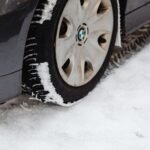 Close-up of a car's tire on a snowy road, highlighting the winter season conditions.
