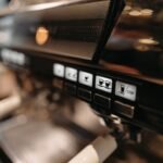 Detailed view of espresso machine panel in a cafe setting, highlighting coffee brewing controls.