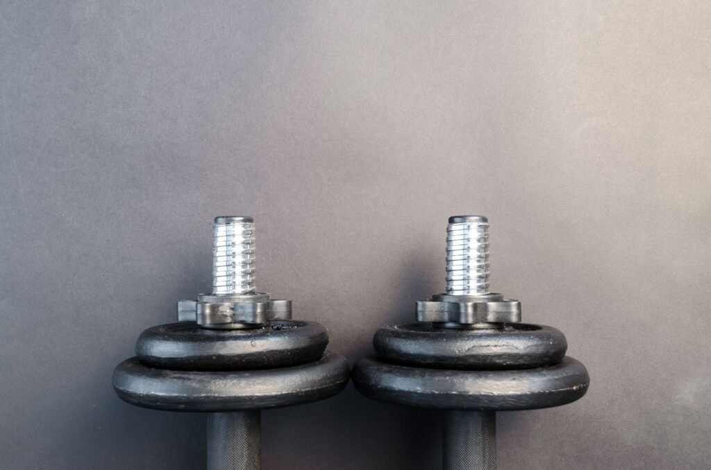 Close-up of two iron dumbbells on a gray background, perfect for strength training images.