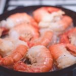 Delicious close-up of prawns sizzling in a frying pan, perfect for seafood lovers.