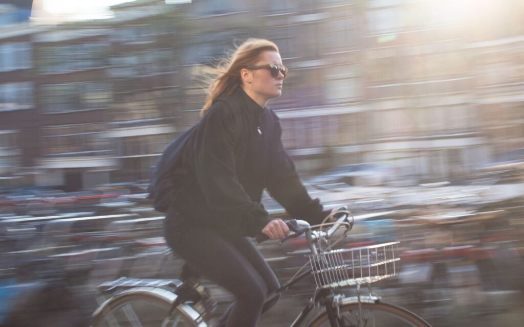 A young woman rides a bicycle quickly through a vibrant urban city, capturing city life and motion.