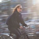 A young woman rides a bicycle quickly through a vibrant urban city, capturing city life and motion.