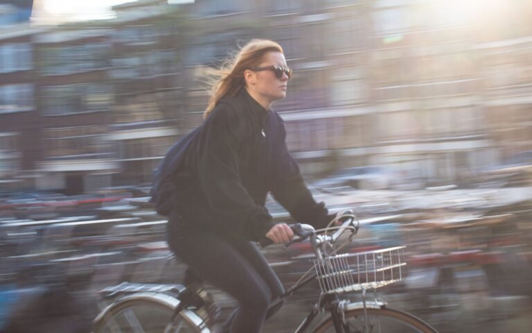 A young woman rides a bicycle quickly through a vibrant urban city, capturing city life and motion.