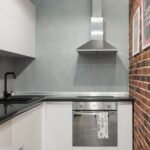Contemporary kitchen interior with stainless steel appliances and brick wall.