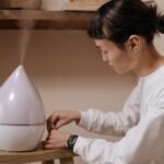 A woman adjusts a humidifier indoors, promoting relaxation and air quality.