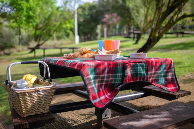 A vibrant picnic scene with food and basket on a table in a lush Portuguese park.