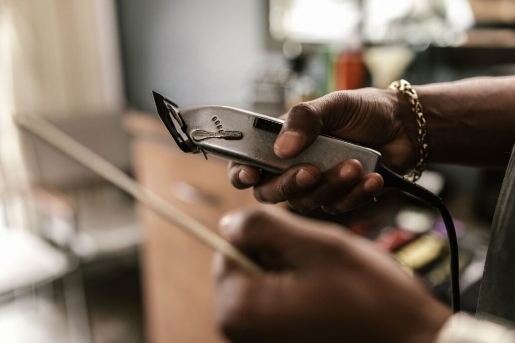 Close-up of a barber holding clippers in a barbershop, focusing on hands and equipment.