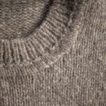 From above of textured backdrop representing warm woolen knitted light gray sweater collar with soft and warm texture