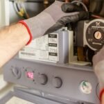 Close-up of hands adjusting a boiler system with precise instrumentation, showing maintenance work.