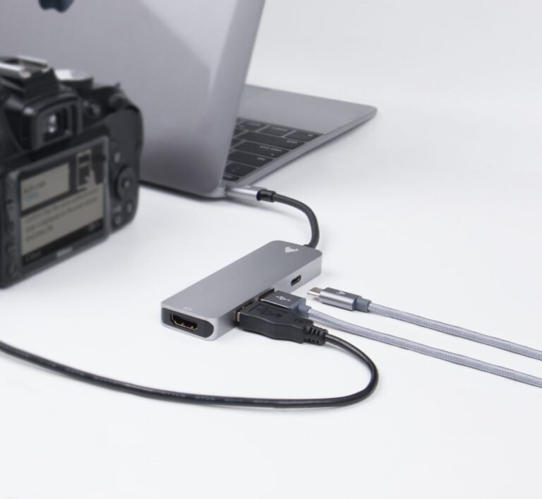 Close-up of a laptop, camera, and connected cables on a desk, depicting modern technology.