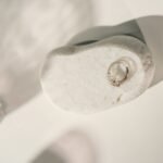 Minimalist silver ring displayed on a smooth white stone with soft lighting, perfect for jewelry showcases.