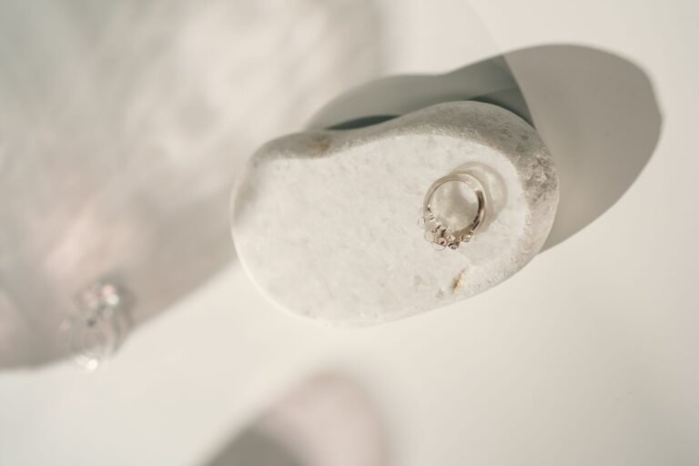 Minimalist silver ring displayed on a smooth white stone with soft lighting, perfect for jewelry showcases.