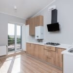Stylish empty kitchen with wooden cabinets and large windows.