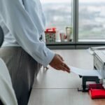 Business professional printing a document in an office environment.
