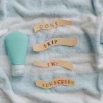 Flat lay of sunscreen bottle with message 'Don't skip the sunscreen' on a towel.