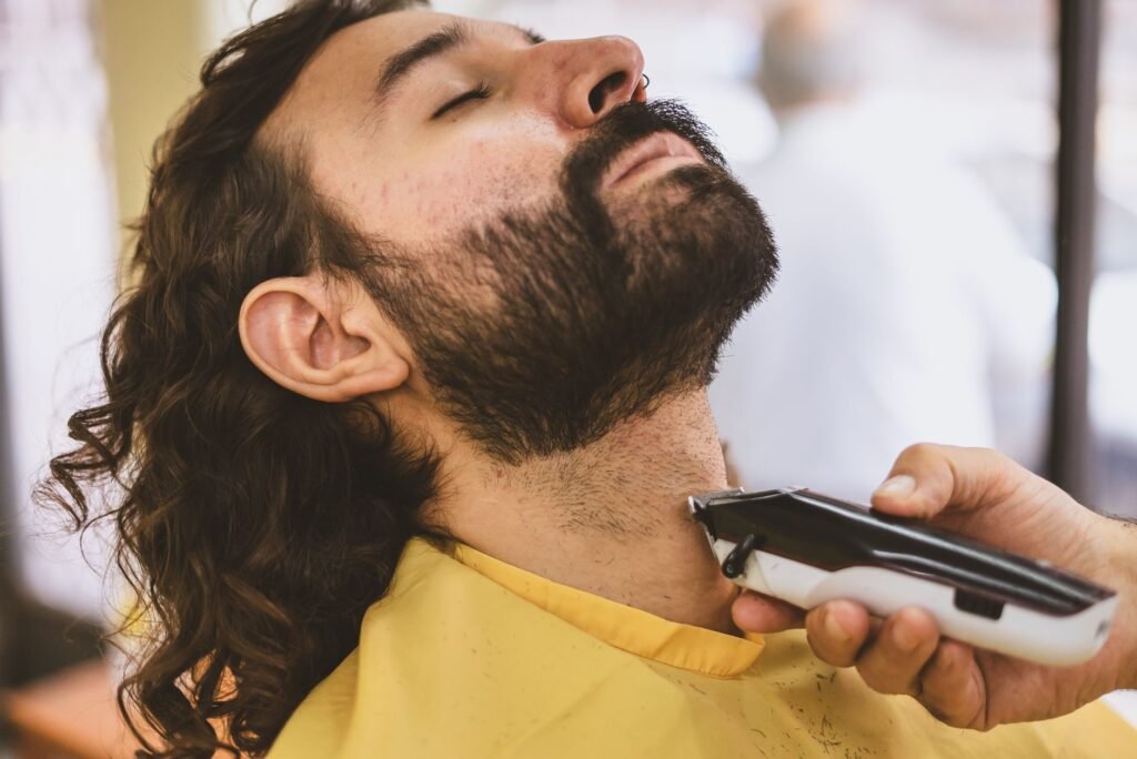 Close-up of a man getting his beard trimmed with an electric shaver.