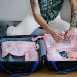 A woman packing her travel suitcase on the floor indoors, preparing for a trip.
