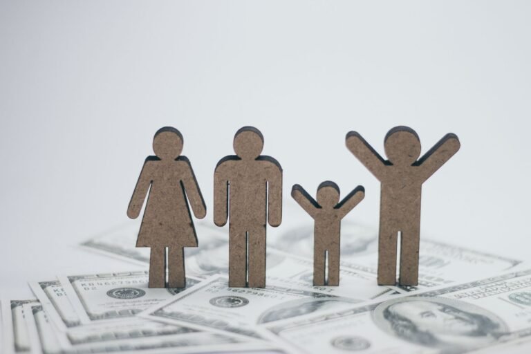 Wooden family figurines on dollar bills symbolizing financial stability.