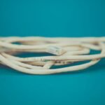 A detailed close-up of a coiled Ethernet cable with an RJ-45 connector against a teal background.
