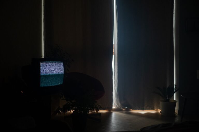 A dimly lit living room with static on the TV and curtains drawn, creating a moody atmosphere.