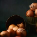 A moody still life of raw onions in rustic containers, showcasing a timeless charm.