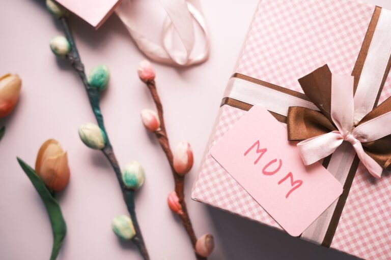 Elegant pink gift box with flowers and a 'Mom' card, perfect for Mother's Day celebrations.