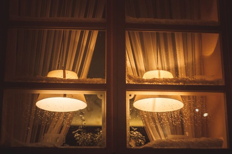A cozy view with warm light through a window during a snowy winter night.