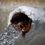 Close-up of water flowing from a rusty pipe with salt deposits, capturing motion and texture.