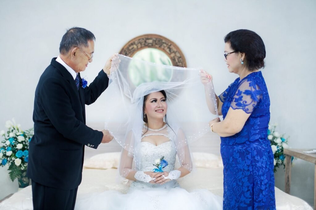 Bride with family in a joyful wedding moment, surrounded by floral decor indoors.