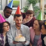 Group of friends celebrating with a birthday cake indoors.