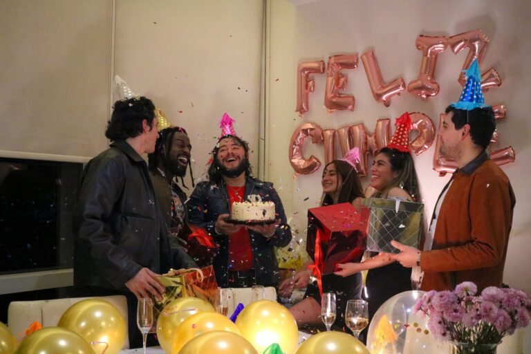 A joyful birthday party with friends, cake, and confetti indoors.
