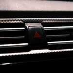 Close-up image of a car hazard light button on a dark dashboard.