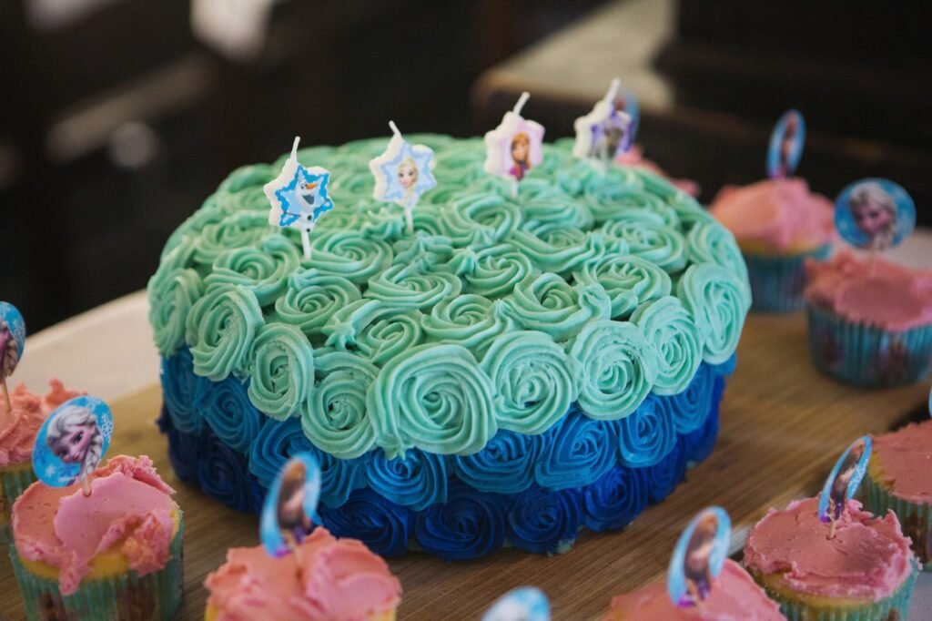 A Frozen-themed birthday cake with blue frosting and matching cupcakes. Perfect for a child's celebration.
