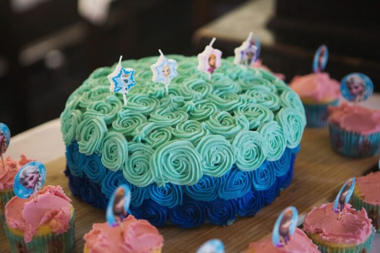 A Frozen-themed birthday cake with blue frosting and matching cupcakes. Perfect for a child's celebration.
