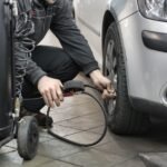Mechanic inspecting and adjusting tire pressure in an auto repair shop.
