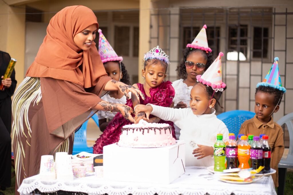 Children celebrating a birthday with cake and party hats, surrounded by friends and family.