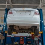 A white Chevrolet car is lifted for maintenance in an automotive repair shop.