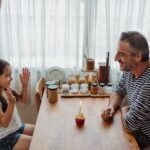Father and daughter celebrating with a cupcake on a joyful day indoors.
