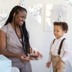 A woman and boy celebrate a birthday with cake and party hats indoors.