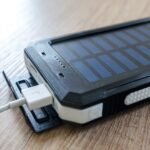 A close-up of a solar charger with a USB connection on a wooden surface, showcasing modern technology.