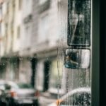 Closeup of wet glass windscreen of bus driving along city in rainy weather