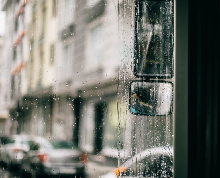 Closeup of wet glass windscreen of bus driving along city in rainy weather