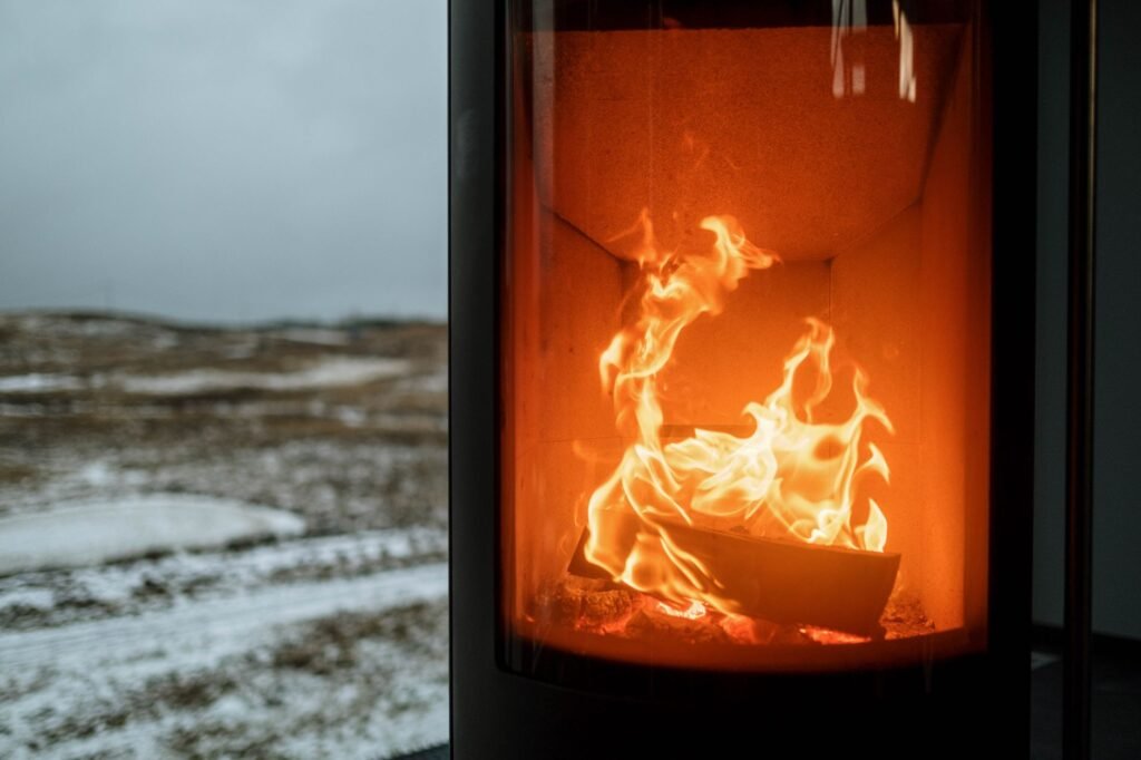 Indoor fireplace with burning flame creating warmth against snowy winter outdoors.
