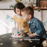 Two children enjoying a birthday celebration at home with a beautiful cake.