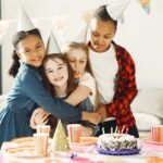 Group of kids enjoying a fun birthday party with cake and hats indoors.