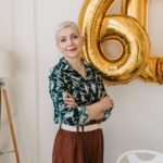 Stylish senior woman posing indoors with 60th birthday balloons, exuding grace and confidence.