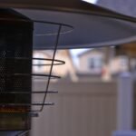 Detailed view of a modern outdoor patio heater with blurred suburban background, perfect for outdoor comfort concepts.