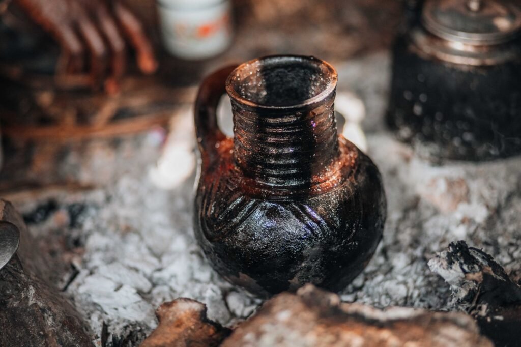 Close-up of a traditional Ethiopian stoneware pot among ashes, highlighting cultural craftsmanship.