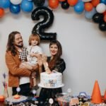 A cheerful family celebrates a child's second birthday with a colorful racing-themed party.